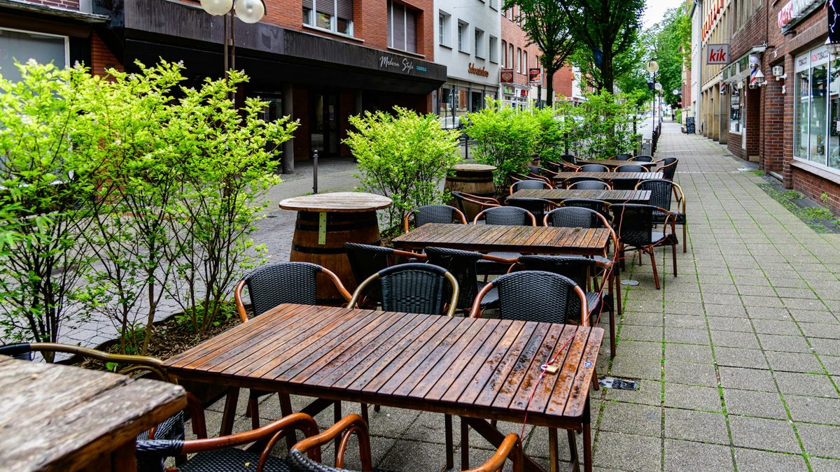 Terrasses de café vides alignées sur un trottoir humide