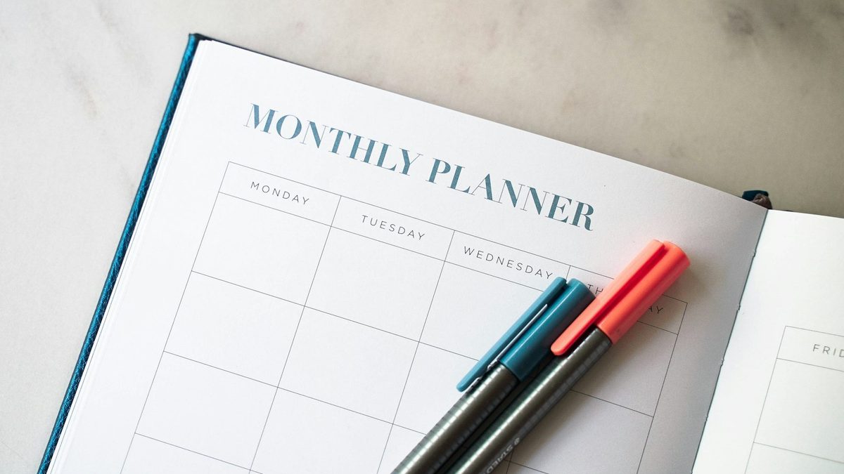 Agenda mensuel ouvert avec deux stylos posés dessus