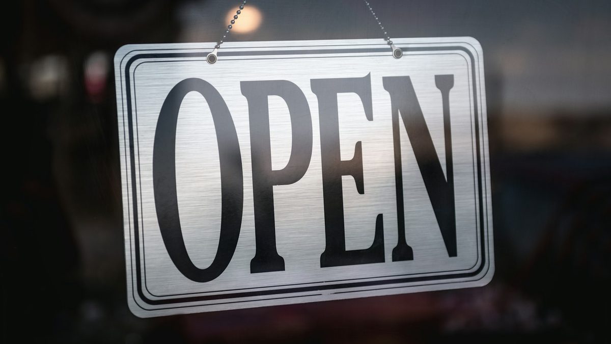 Panneau « Open » accroché derrière la vitre d'un commerce
