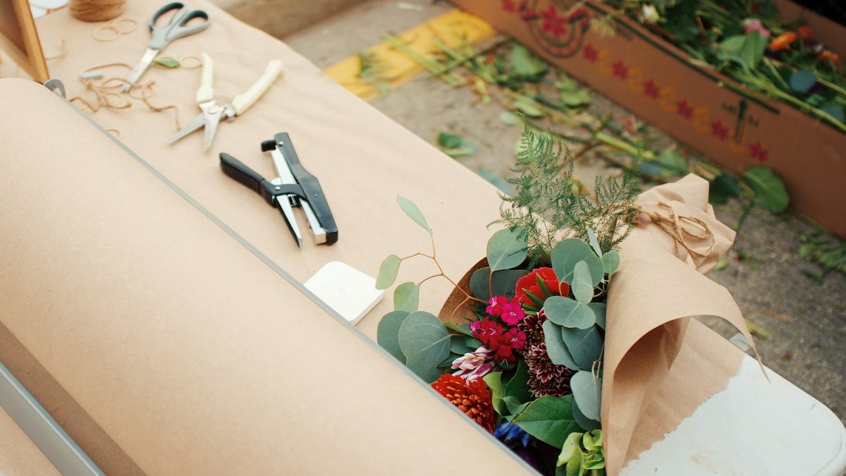 Table d'emballage avec papier kraft, sécateurs et bouquet de fleurs