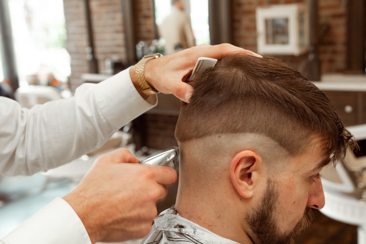 Barbier réalisant une coupe dégradée à la tondeuse